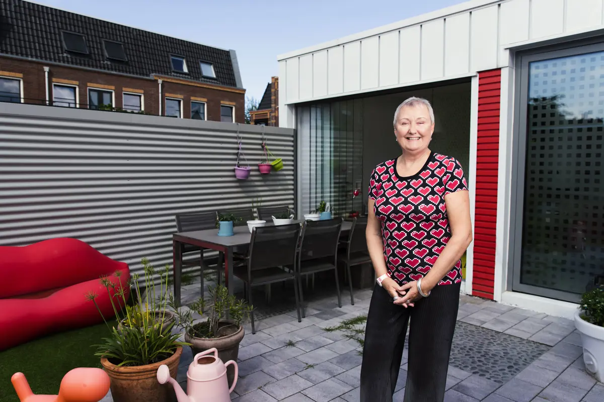 Vrouw in achtertuin van haar duurzame woning gebouwd van zeecontainers