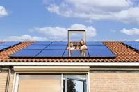Gezin kijkt door het dakraam naar buiten. Op he dak liggen 10 zonnepanelen.
