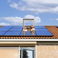 Gezin kijkt door het dakraam naar buiten. Op he dak liggen 10 zonnepanelen.