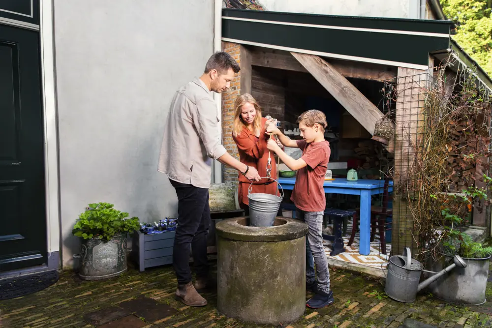 Gezin staat bij waterpomp