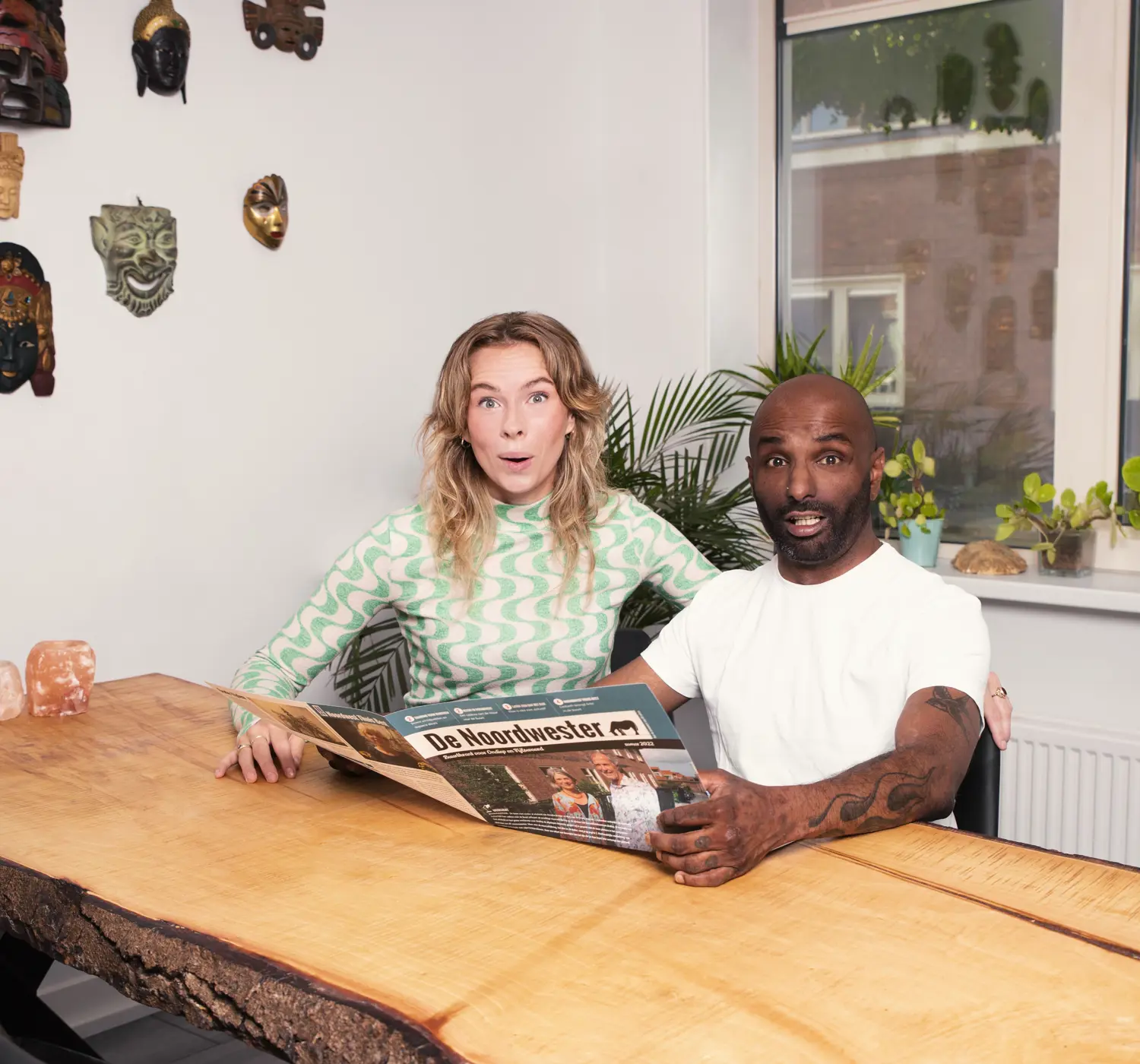 Stel leest aan de eettafel een tijdschrift.